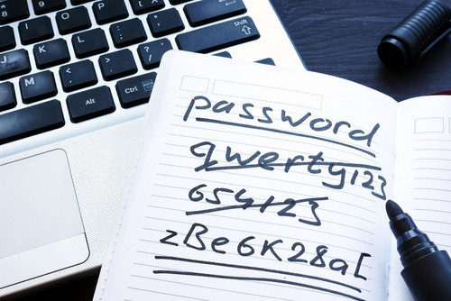 Laptoptastatur und Papierzettel mit Wort password und diversen Buchstabenzahlenkombination-